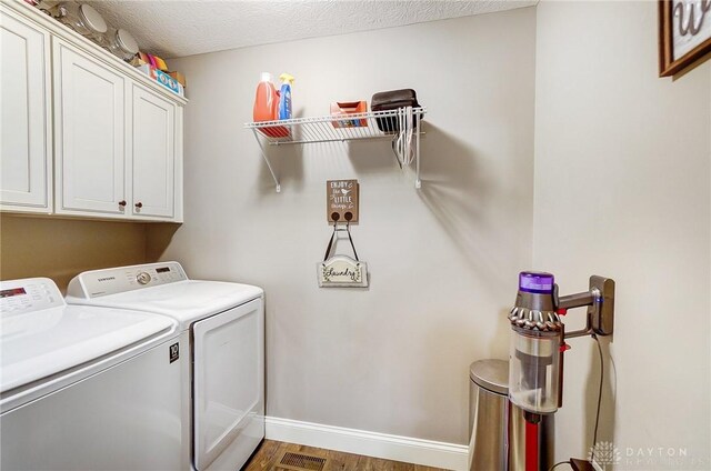 laundry room featuring cabinets, a textured ceiling, dark hardwood / wood-style flooring, and washer and clothes dryer