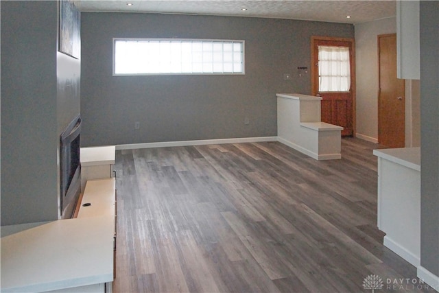 unfurnished living room with a textured ceiling, plenty of natural light, and dark wood-type flooring