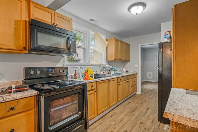 kitchen with light wood-type flooring and black appliances