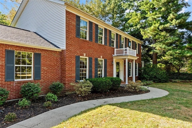 colonial-style house with a balcony and a front lawn