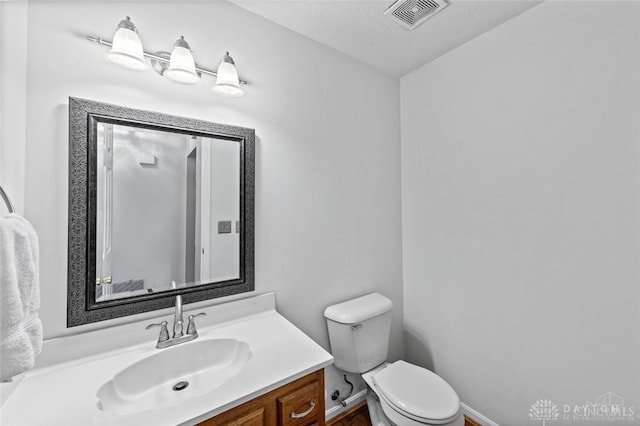 bathroom with a textured ceiling, vanity, and toilet