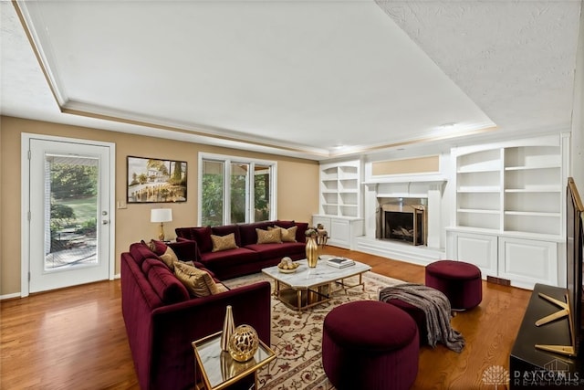 living room featuring hardwood / wood-style flooring, a raised ceiling, a high end fireplace, and a wealth of natural light