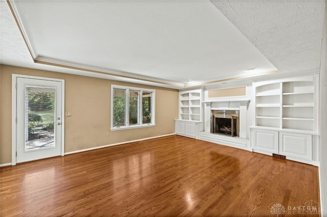 unfurnished living room with a textured ceiling, a raised ceiling, and hardwood / wood-style flooring