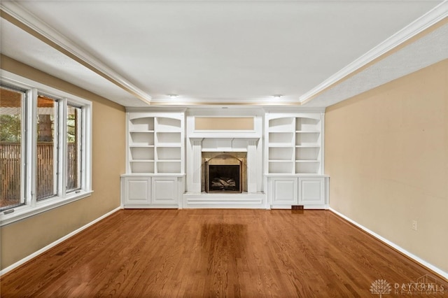 unfurnished living room featuring hardwood / wood-style flooring, a tray ceiling, and ornamental molding