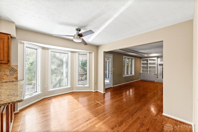 unfurnished living room with ceiling fan, plenty of natural light, and hardwood / wood-style floors