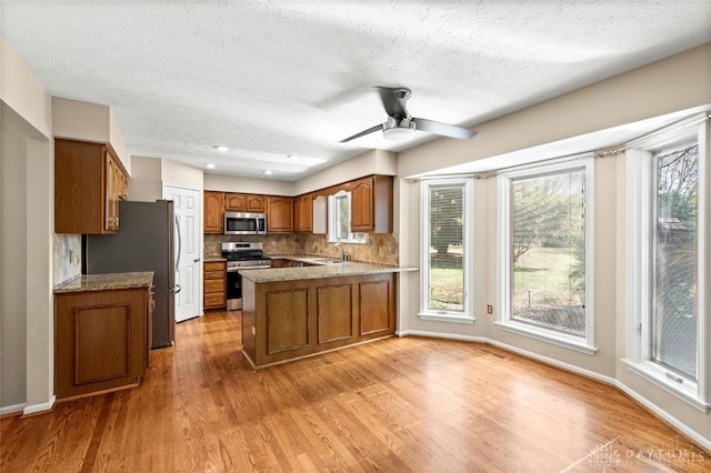 kitchen featuring kitchen peninsula, ceiling fan, appliances with stainless steel finishes, and a healthy amount of sunlight