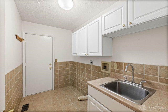 kitchen with tile walls, white cabinetry, light tile patterned flooring, and sink