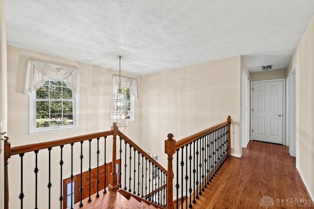 staircase featuring wood-type flooring, a textured ceiling, and a chandelier