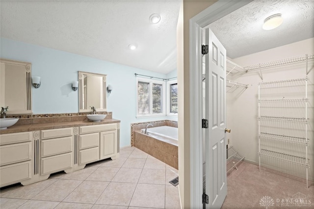 bathroom featuring vanity, a relaxing tiled tub, tile patterned flooring, and a textured ceiling