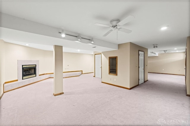 basement with ceiling fan, light colored carpet, and a fireplace