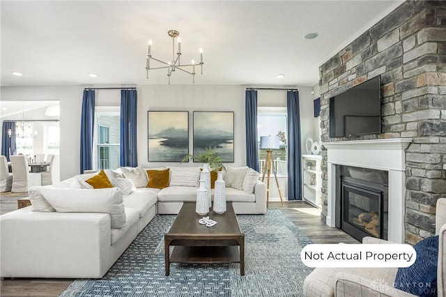 living room featuring hardwood / wood-style floors, a wealth of natural light, a fireplace, and a chandelier