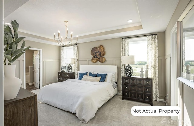 bedroom featuring ensuite bathroom, ornamental molding, a tray ceiling, a notable chandelier, and light colored carpet