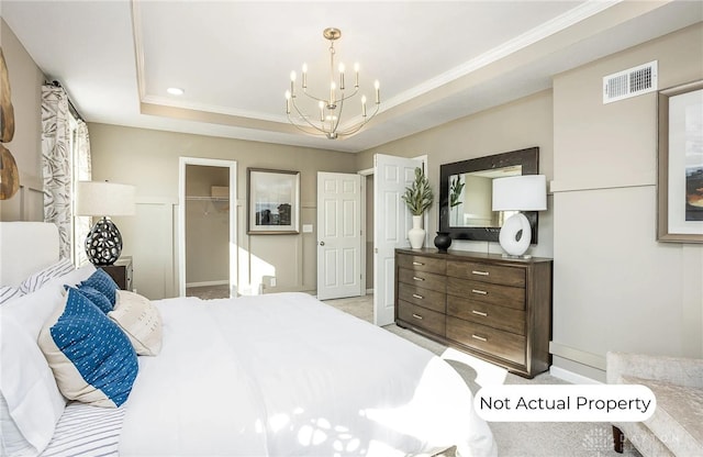 carpeted bedroom with ornamental molding, a walk in closet, a raised ceiling, an inviting chandelier, and a closet