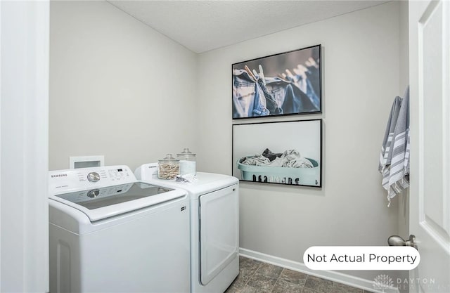 clothes washing area with washing machine and clothes dryer and a textured ceiling