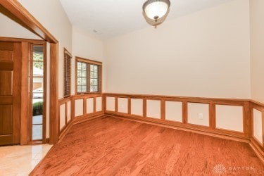unfurnished room with wainscoting, wood finished floors, and a decorative wall