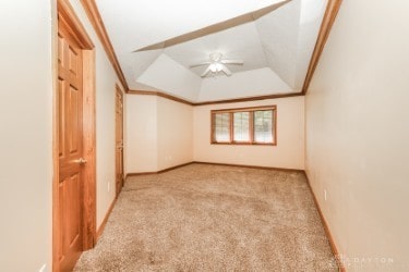 interior space with baseboards, ceiling fan, ornamental molding, and a tray ceiling