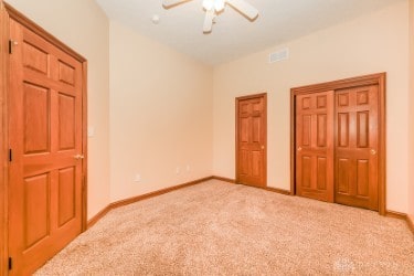 unfurnished bedroom featuring visible vents, baseboards, ceiling fan, vaulted ceiling, and carpet flooring