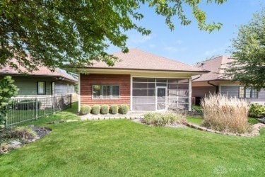 back of property with a sunroom, fence, and a yard