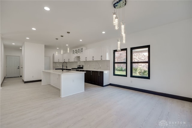 kitchen featuring white cabinetry, pendant lighting, an island with sink, and light wood-type flooring