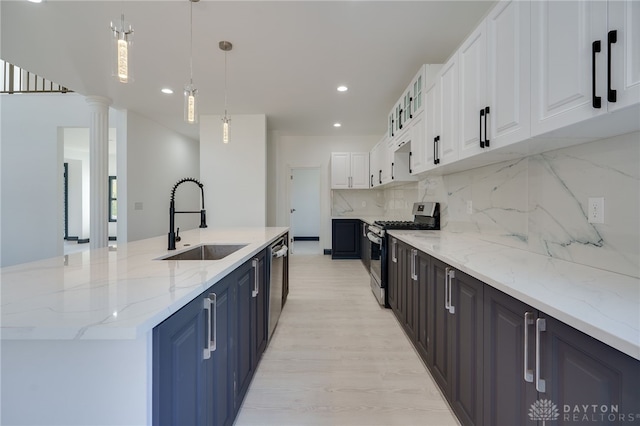 kitchen featuring white cabinetry, appliances with stainless steel finishes, ornate columns, decorative backsplash, and sink