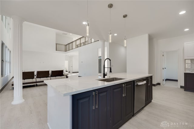 kitchen with ornate columns, stainless steel dishwasher, a kitchen island with sink, and sink