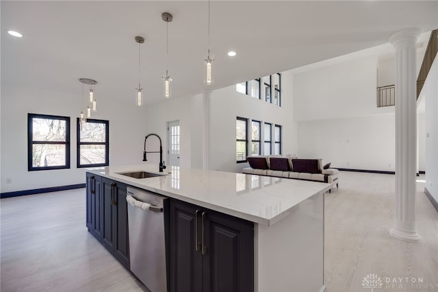 kitchen featuring decorative light fixtures, stainless steel dishwasher, sink, and light hardwood / wood-style flooring