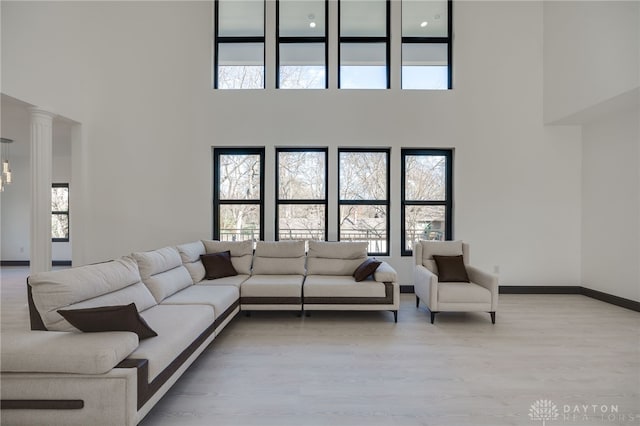 living room with light wood-type flooring, a high ceiling, and decorative columns