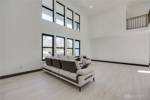 living room featuring light wood-type flooring and a towering ceiling