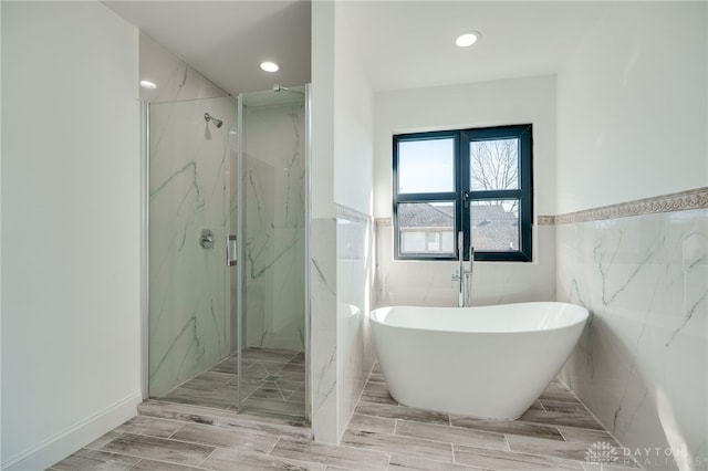 bathroom featuring plus walk in shower and tile walls