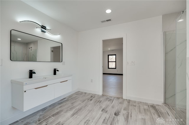 bathroom with hardwood / wood-style floors, vanity, and a shower