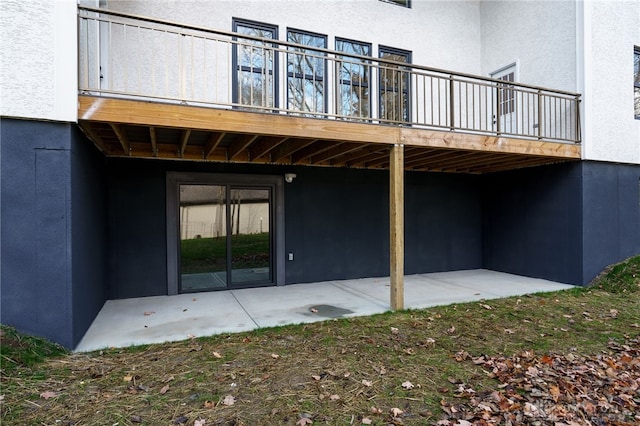 back of property with a wooden deck and a patio