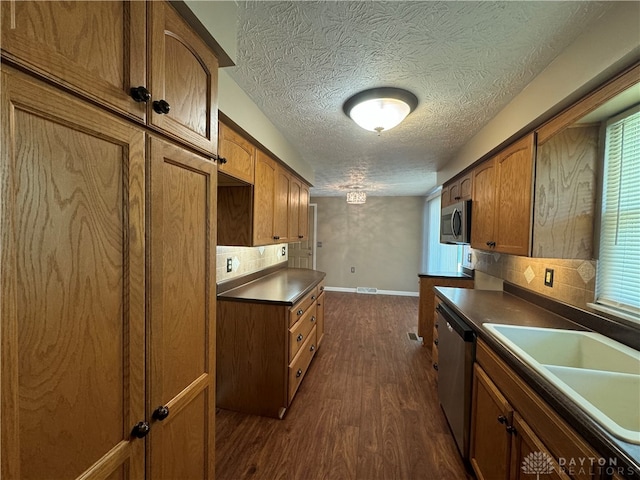 kitchen with a textured ceiling, dark wood-type flooring, sink, backsplash, and appliances with stainless steel finishes