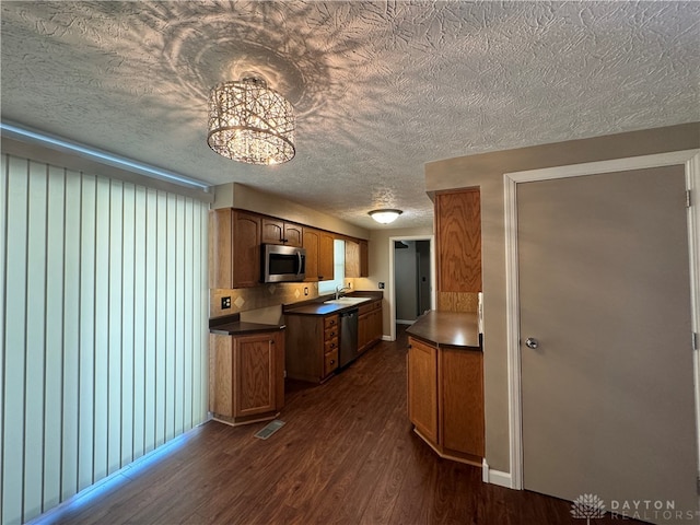 kitchen with a textured ceiling, tasteful backsplash, sink, appliances with stainless steel finishes, and dark hardwood / wood-style flooring