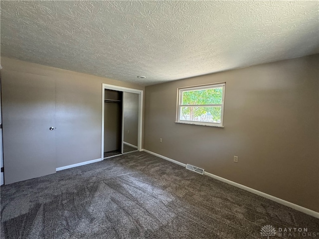 unfurnished bedroom with a textured ceiling, a closet, and carpet