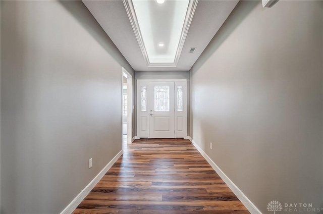 doorway to outside featuring a raised ceiling, crown molding, and dark hardwood / wood-style flooring