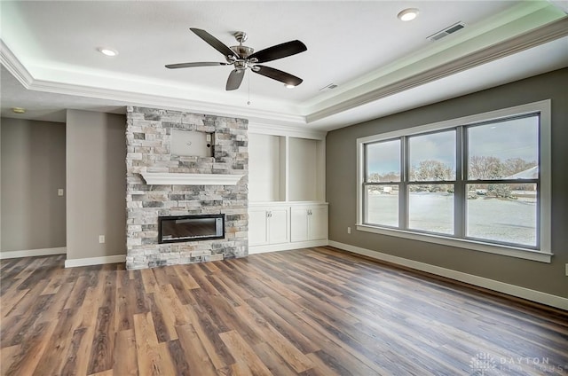 unfurnished living room featuring a fireplace, a tray ceiling, and a healthy amount of sunlight