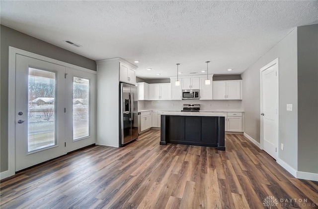 kitchen featuring white cabinets, decorative light fixtures, and appliances with stainless steel finishes