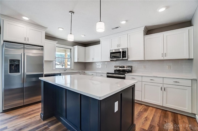 kitchen with a center island, stainless steel appliances, dark hardwood / wood-style floors, pendant lighting, and white cabinets