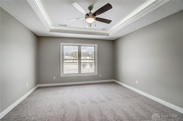 carpeted spare room featuring a raised ceiling, ceiling fan, and ornamental molding