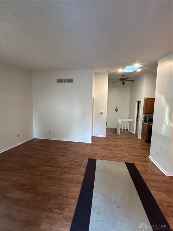 spare room featuring a skylight, ceiling fan, and dark hardwood / wood-style flooring