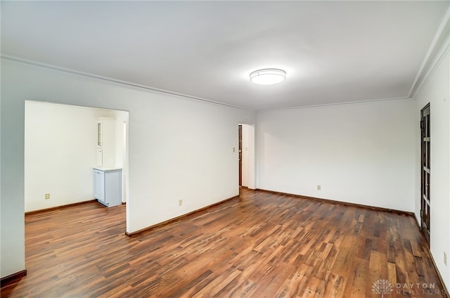 empty room featuring dark wood-type flooring and crown molding