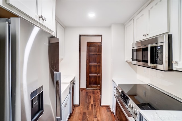 kitchen with appliances with stainless steel finishes, tasteful backsplash, hardwood / wood-style floors, and white cabinets