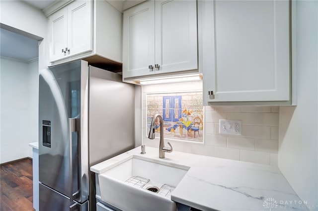 kitchen with light stone counters, white cabinets, dark hardwood / wood-style flooring, stainless steel refrigerator with ice dispenser, and sink