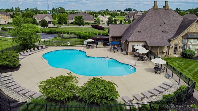 community pool featuring a patio, a lawn, and fence