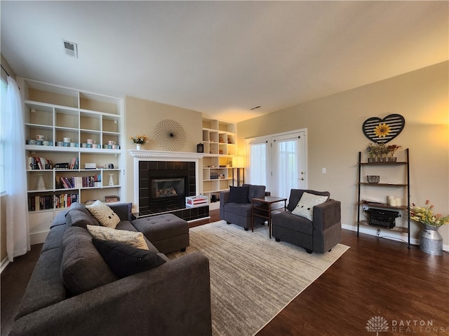 living room with a tiled fireplace and dark hardwood / wood-style floors