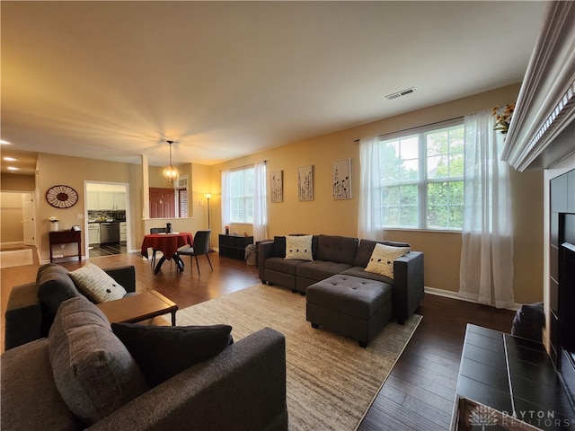 living room with a tile fireplace, dark hardwood / wood-style floors, and a chandelier