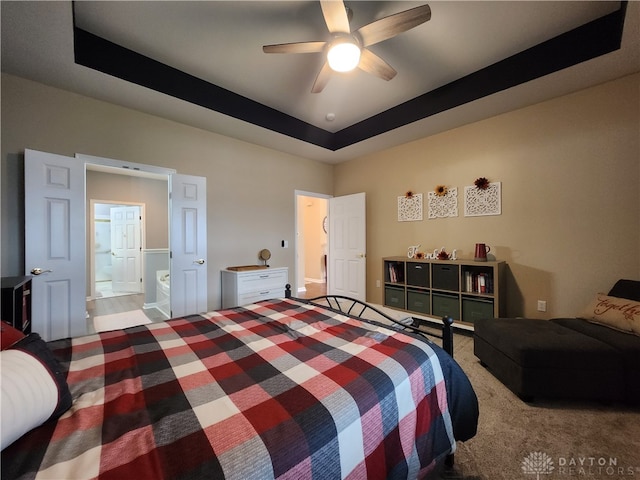 bedroom featuring connected bathroom, ceiling fan, and a raised ceiling