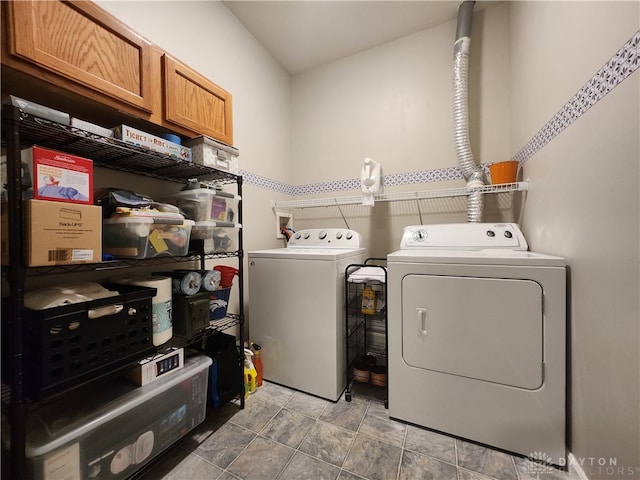 clothes washing area with washer and clothes dryer and cabinets