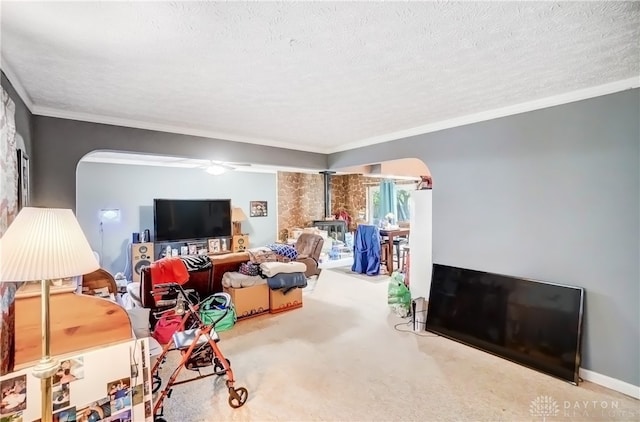 carpeted living room with ornamental molding, a wood stove, a textured ceiling, and ceiling fan