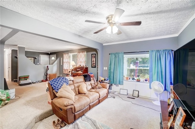 living room featuring carpet floors, a textured ceiling, ornamental molding, and ceiling fan